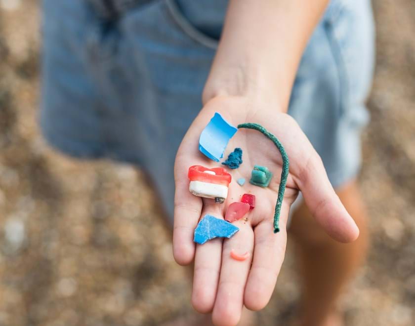 Child's hand holding pieces of plastic pollution