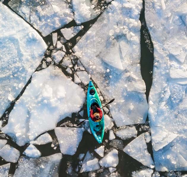 Man kayaking through ice