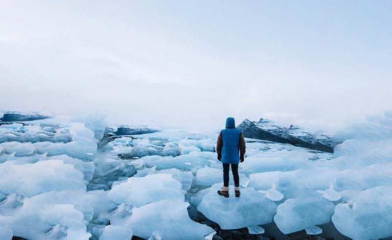 Man stood on icy waters, from behind