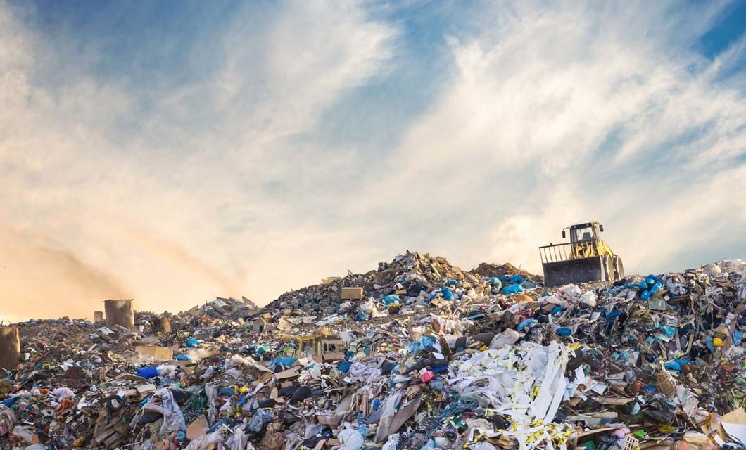 Bulldozer at a landfill site full of plastic
